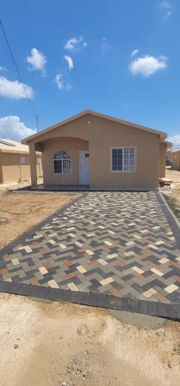 a house with a checkered driveway in front of it at Cozy Escape 876 Secure 2BR with AC, Parking & near Beaches in Portmore