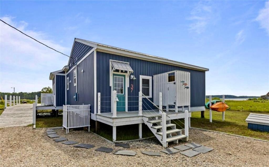 a blue tiny house with a porch and stairs at Salt & Pine in Mathews, VA in Blackwater