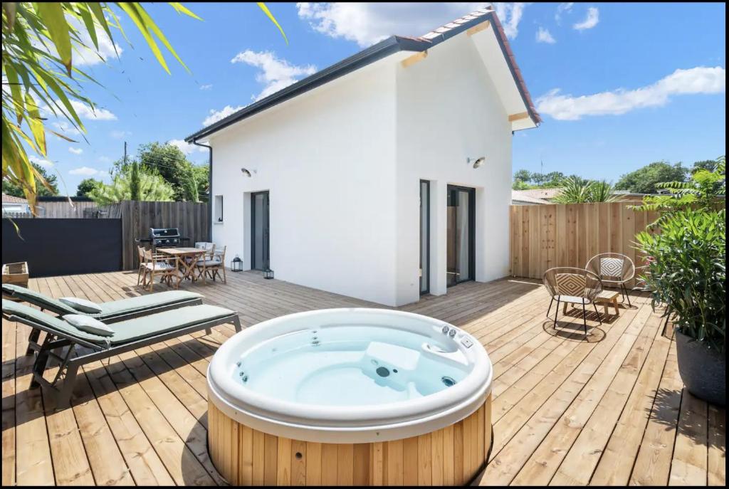 a hot tub on a wooden deck with a house at TI KASA et SPA in Andernos-les-Bains
