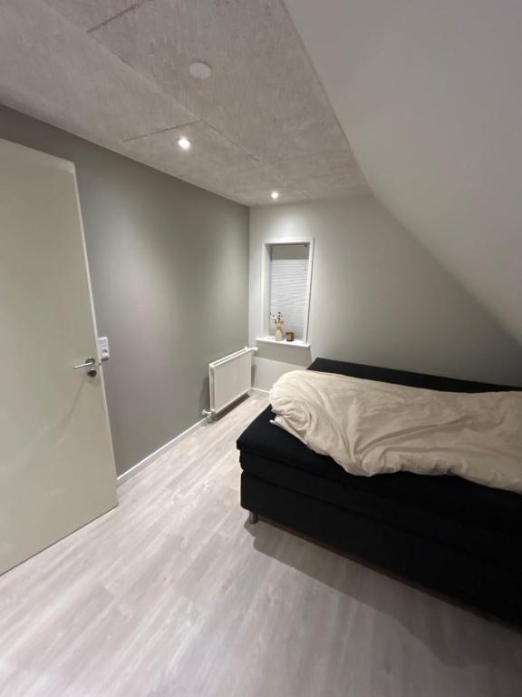 a bedroom with a bed and a white wall at Grønningen Retreat in Billund