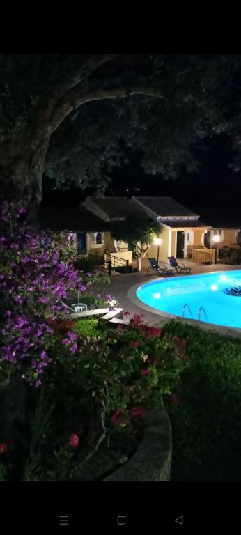 a swimming pool with purple flowers next to a resort at Aphrodite Studios & Pool in Paleokastritsa