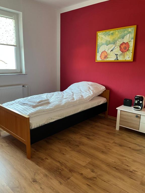 a bed in a room with a red wall at Ferienwohnung Fatlume No 5 n 6 in Bad Honnef am Rhein