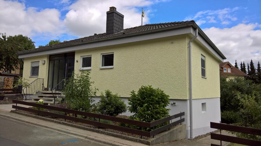 a yellow and white house with a fence at Ferienwohnung DORFWIESE in NuÃŸbaum
