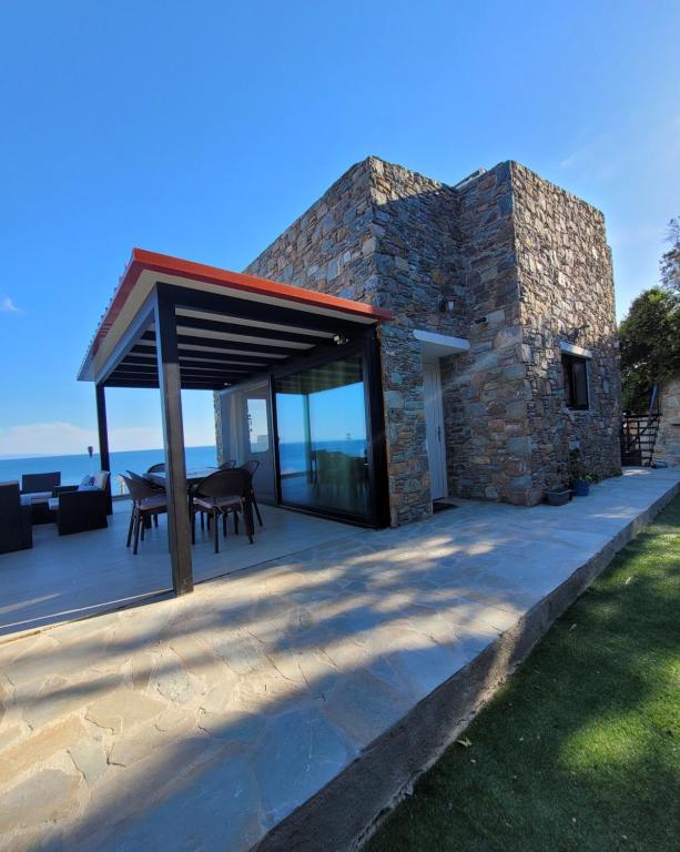 a stone house with a roof on a patio at La Mer Villa - Entire Cottage in Plomari
