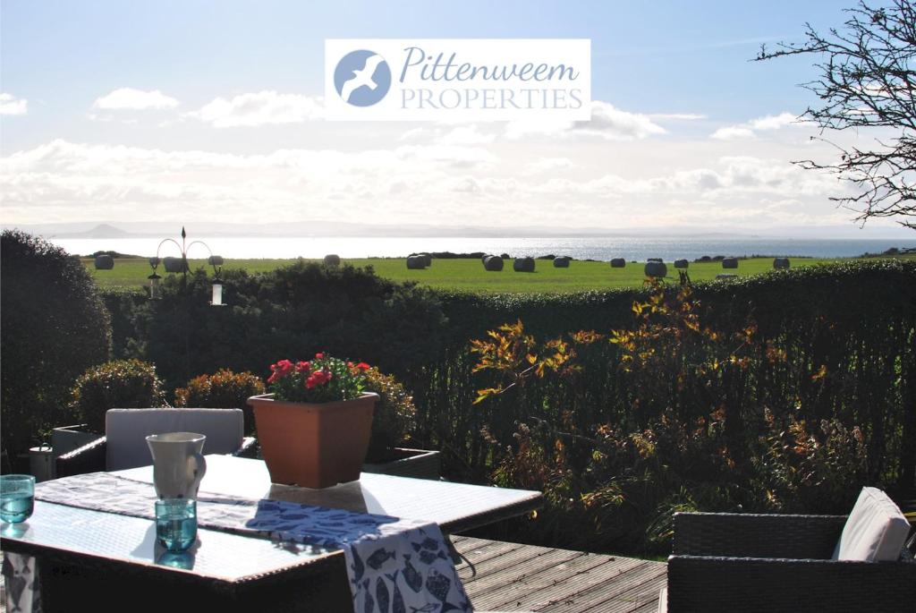 a patio with a table with a view of a field at Mill View Cottage- charming coastal cottage in Saint Monance