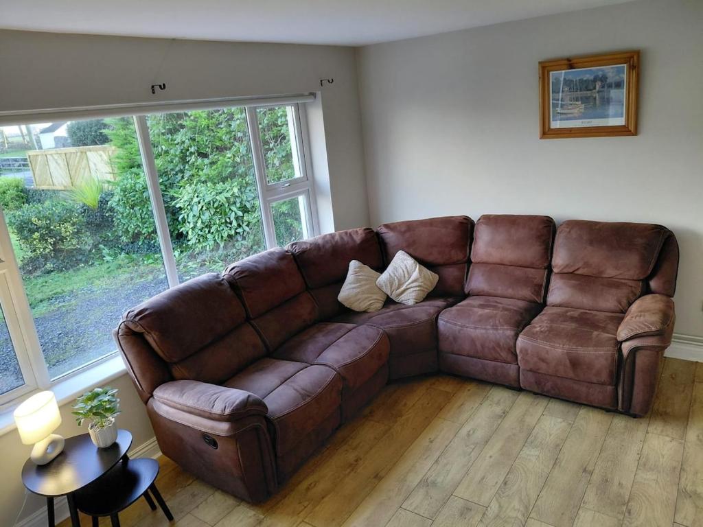 a brown leather couch in a living room with a window at GiGi's Bungalow in Galway