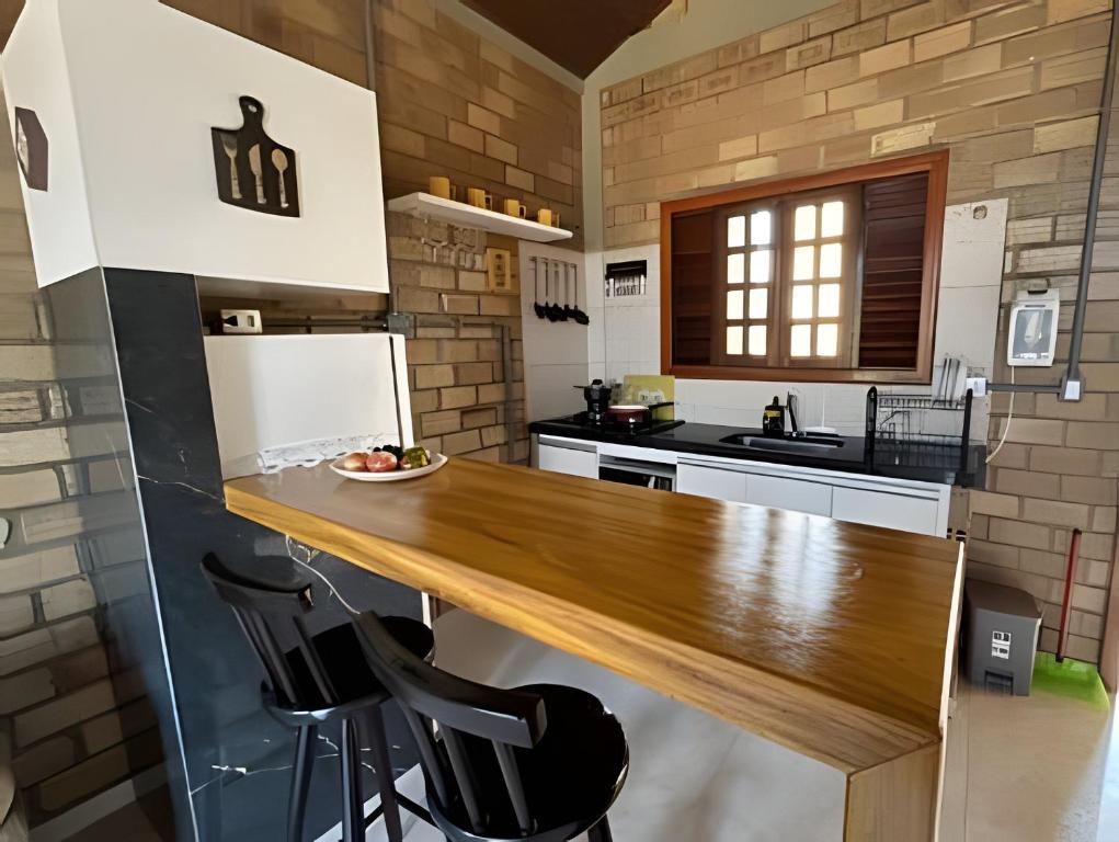 a kitchen with a wooden table and black chairs at Bella Casa Ipê 1º andar APA Barra de Mamanguape in Rio Tinto
