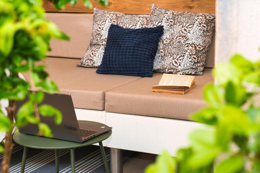 a laptop on a table next to a couch with pillows at Central Beach Retreat in Trogir