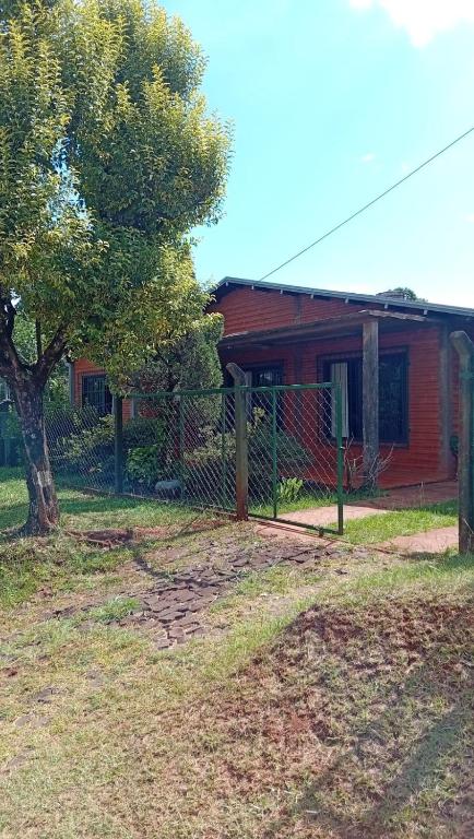 a fence in front of a red house with a tree at Casa Paganelli Germano in Aristóbulo del Valle
