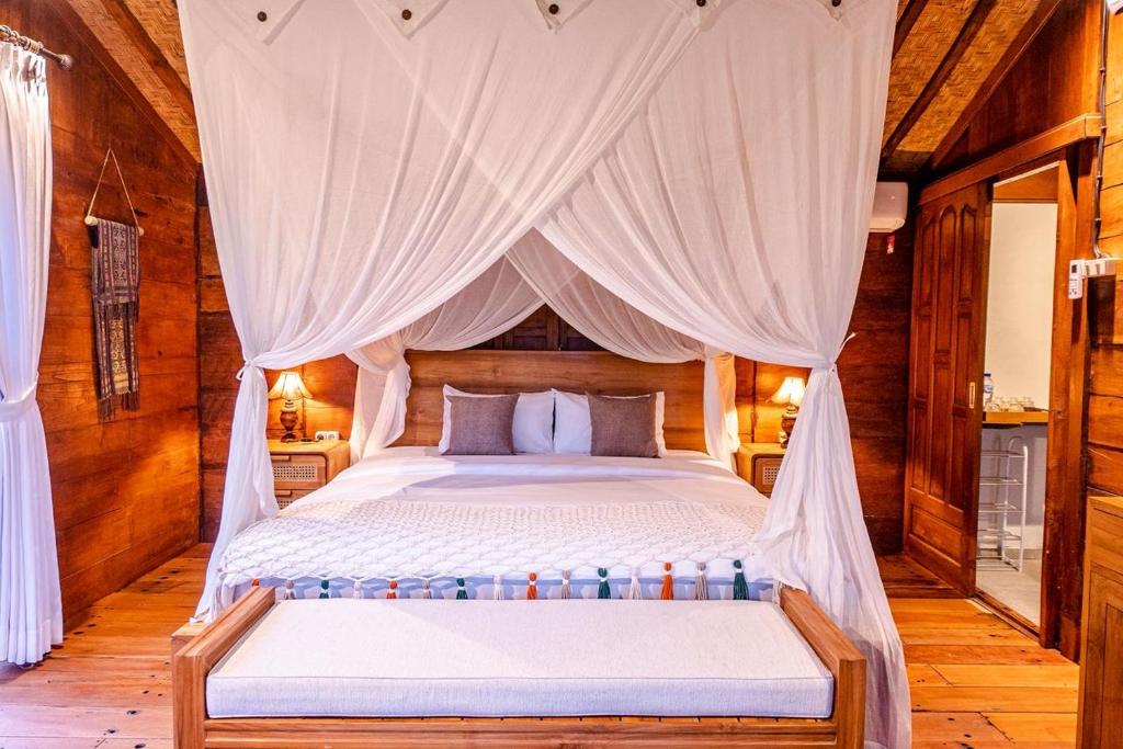 a bedroom with a canopy bed with white curtains at Umah Jati Villa in Gianyar