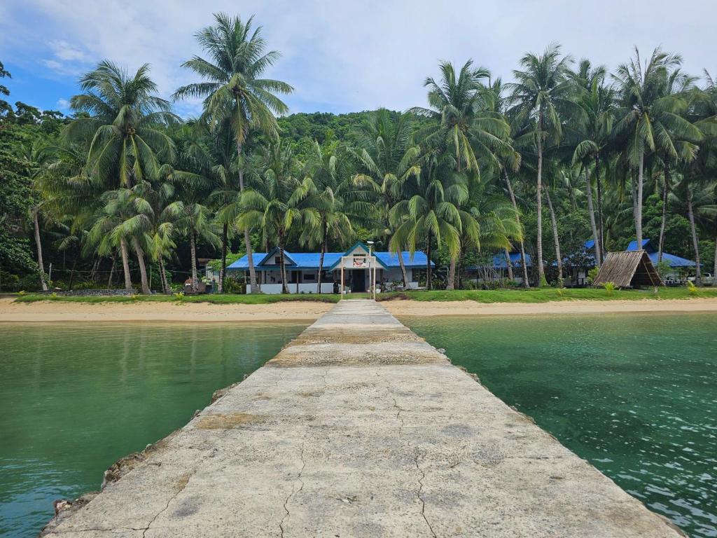 a pier leading to a beach with palm trees at DK2 Resort - Remote Beach Hideaway - Fast WiFi - Private Tours by Arrangement - Plan Ahead in El Nido