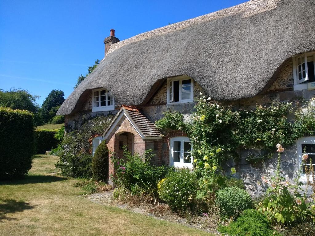 an old stone cottage with a thatched roof at The Cottage in Fyfield