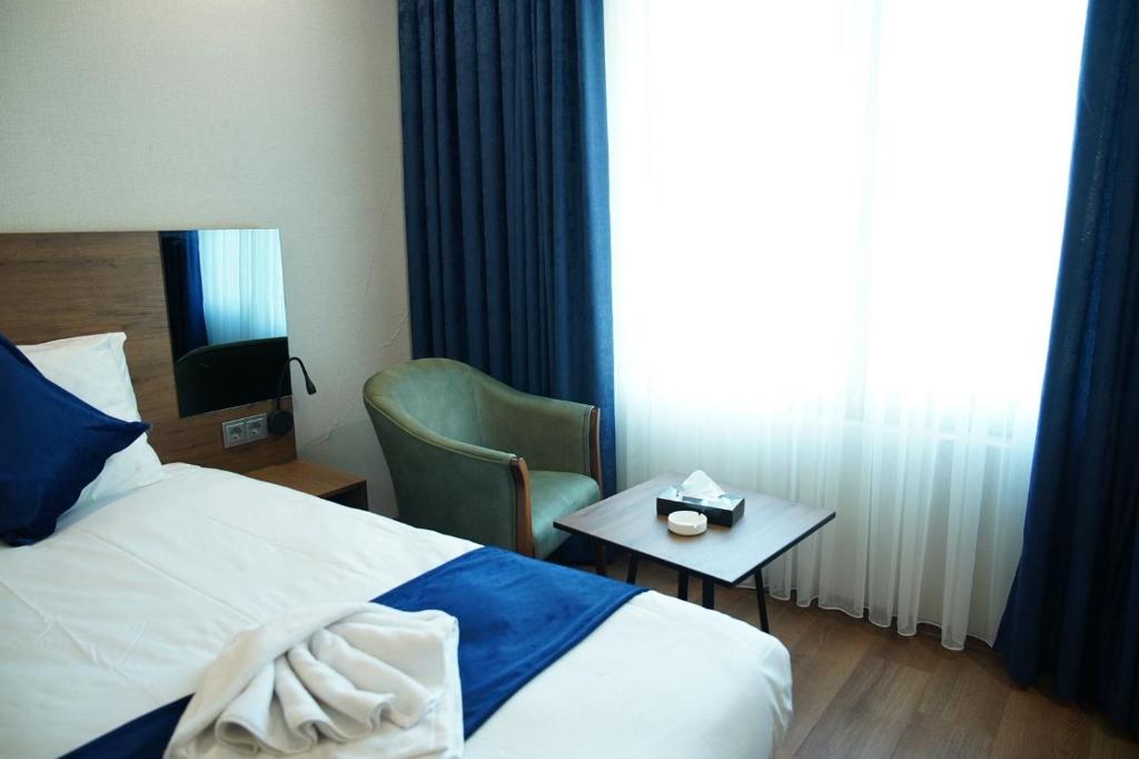 a hotel room with a bed and a table and a window at Erbil Platinum Hotel in Erbil
