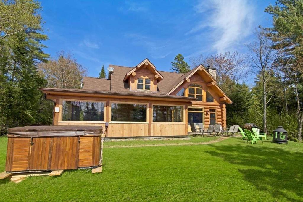 a log home with a hot tub in the yard at Merle Bleu in Wentworth