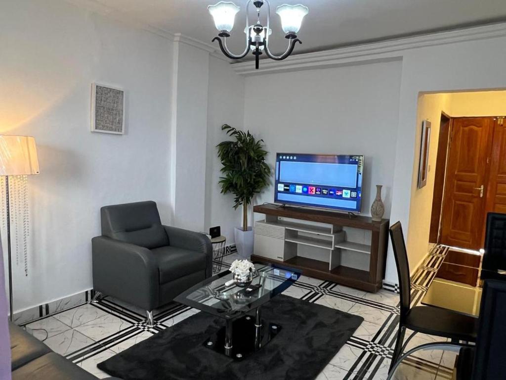 a living room with a chair and a television at TOU R serjo polo in Douala