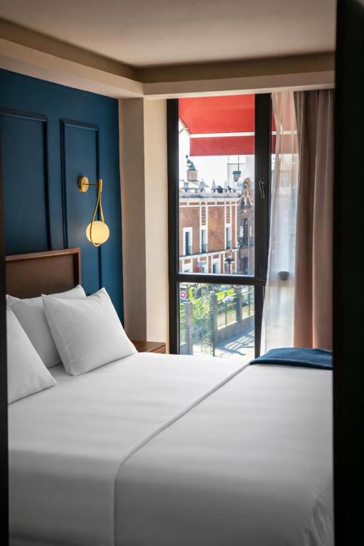 a bedroom with a large white bed and a window at Priede Hotel Boutique in Puebla