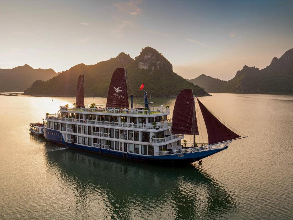 a cruise ship on the water with mountains in the background at Xanh Cat Ba Hotel in Cat Ba