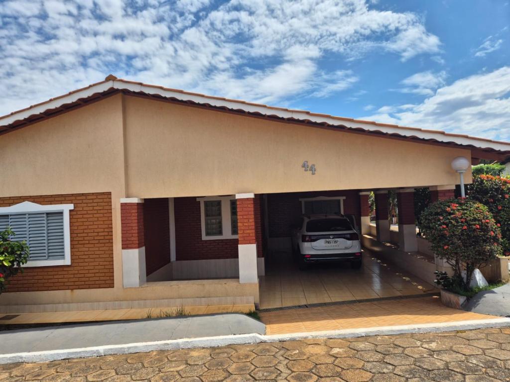 a small house with a car parked in the garage at Chalé dos Marques in Caldas Novas