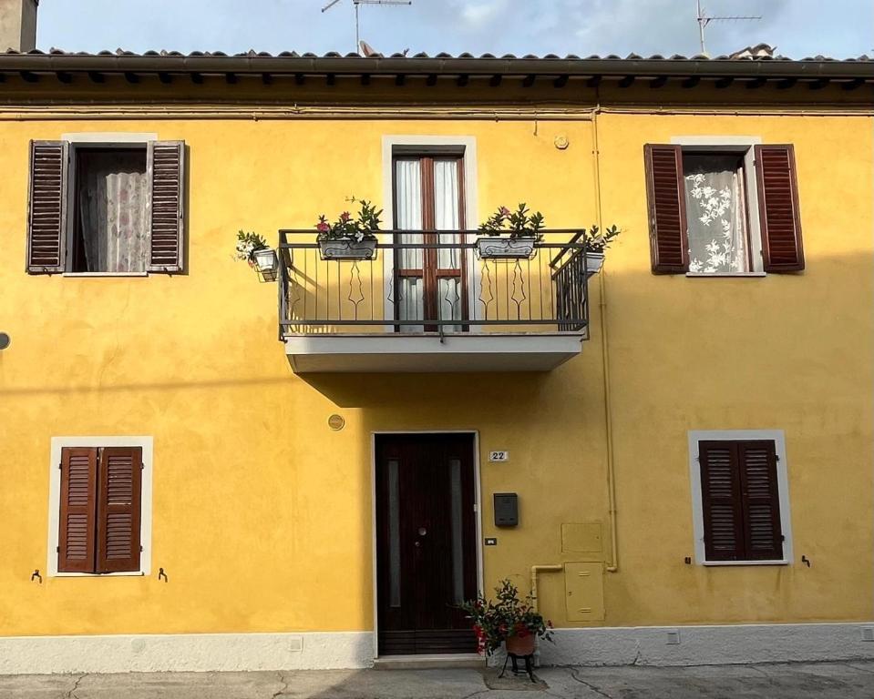 a yellow building with a balcony and a door at B&b DALLA FE in Fermignano