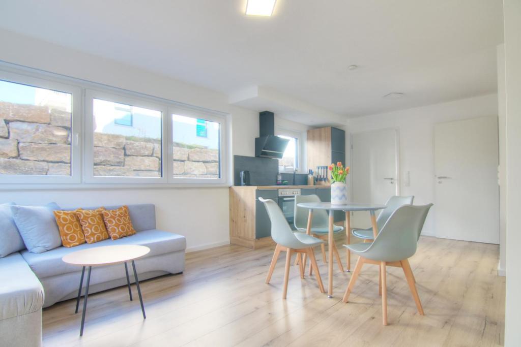 a living room with a couch and a table and chairs at Modernes Wohlfühl-Apartment mit Glasfaser-WLAN, Parkplatz in der Nähe & Küche in Bad Wimpfen in Bad Wimpfen