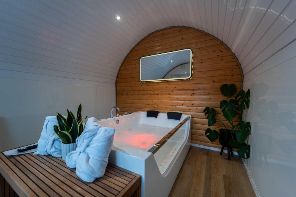 a bathroom with a tub with a wooden wall at Apex Studio Pod and Jacuzzi Bath in Fort William