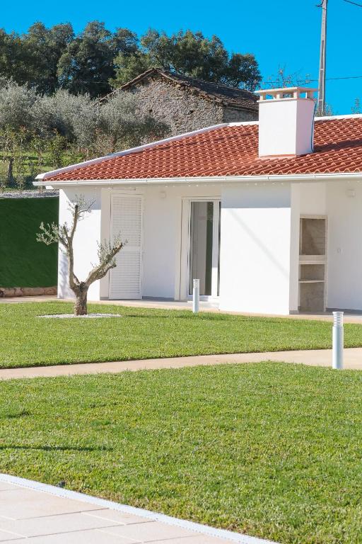 a white house with a tree in the yard at Casa do Santo Estevão in Macedo de Cavaleiros