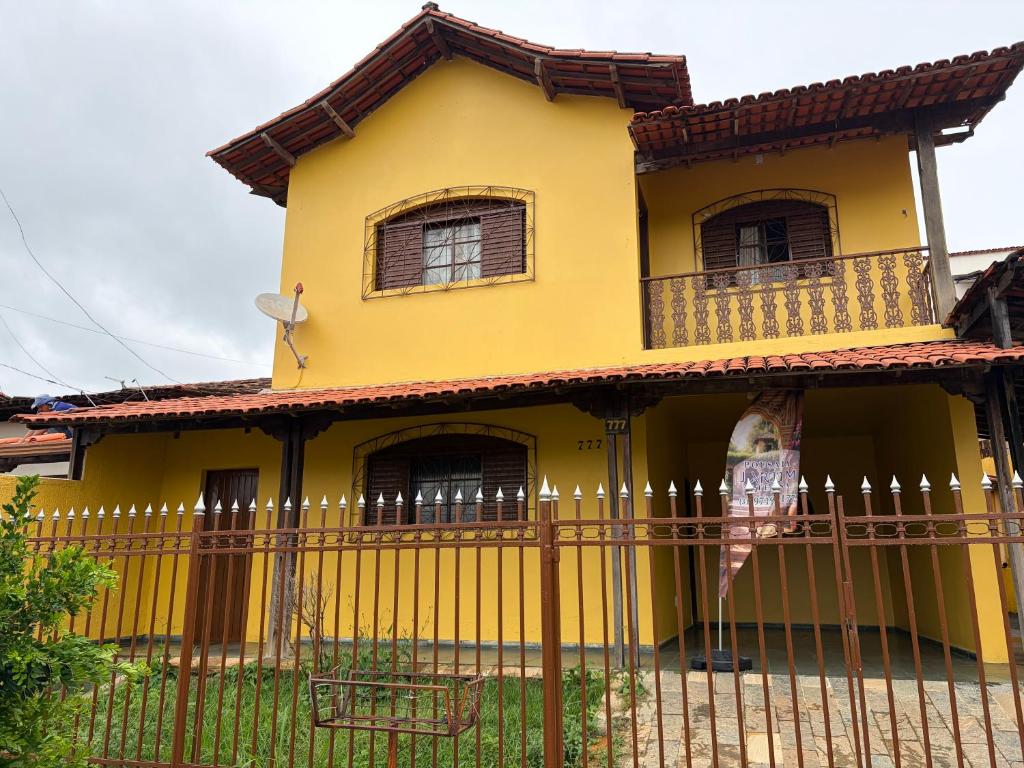 a yellow house with a fence in front of it at Pousada Jardim Alterosa in Vespasiano