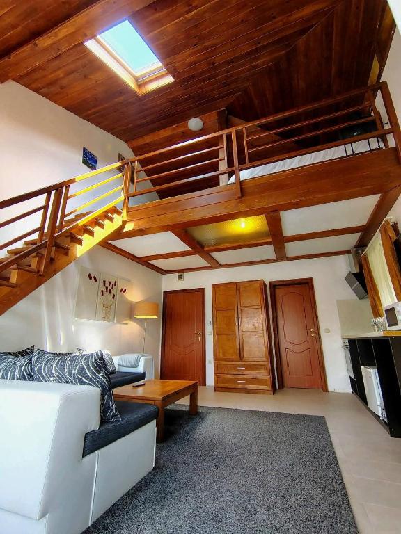 a living room with a white couch and a loft at Homely in Bansko