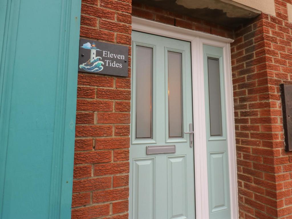 a door to a brick building with a sign on it at Eleven Tides in Seaham