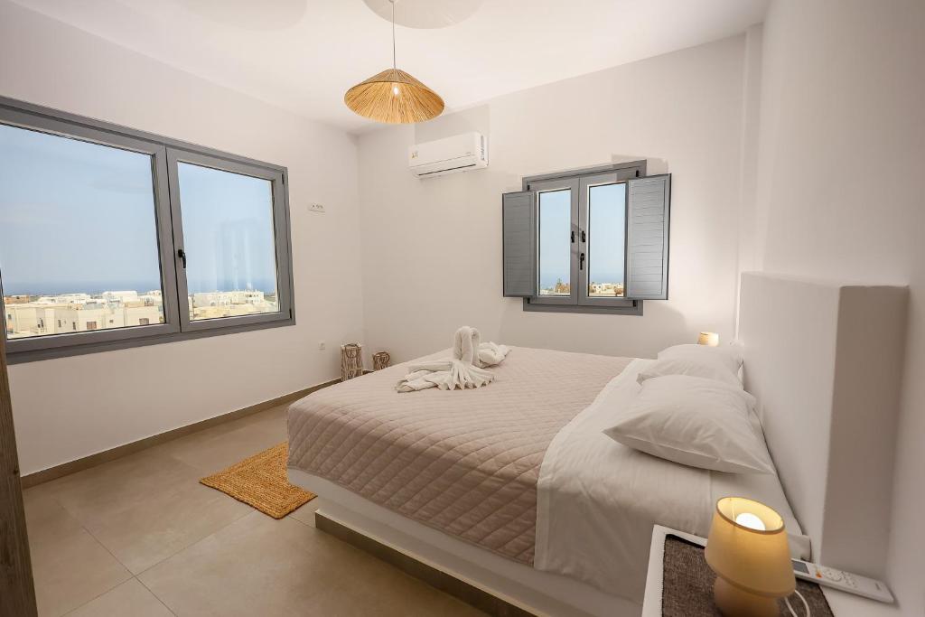 a white bedroom with a bed and two windows at Aerial Apartments in Karterados