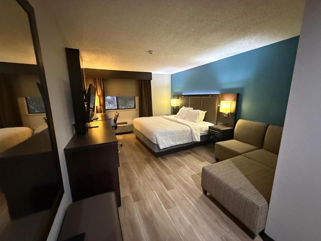 a hotel room with a bed and a couch at Quality Inn & Suites Detroit Metro Airport in Romulus
