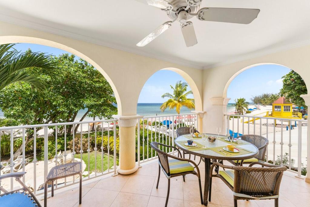 a room with a balcony with a table and chairs and the ocean at 101 Sapphire Beach Barbados in Christ Church