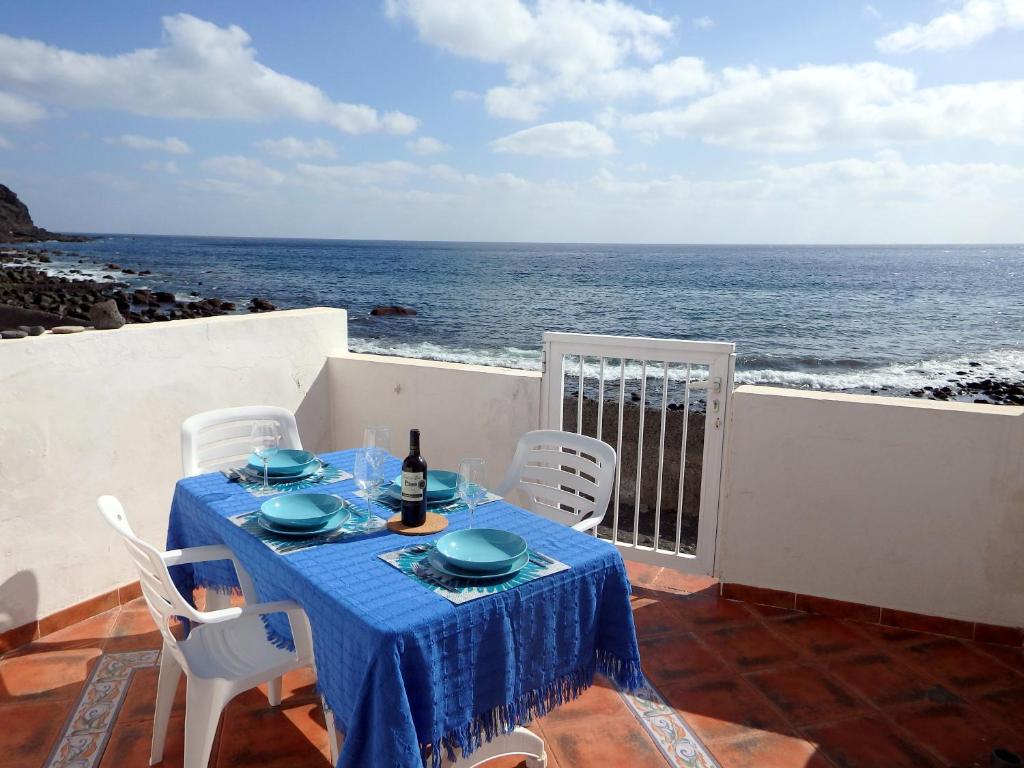 una mesa con un mantel azul en un balcón con vistas al océano en El Varadero, en Igueste