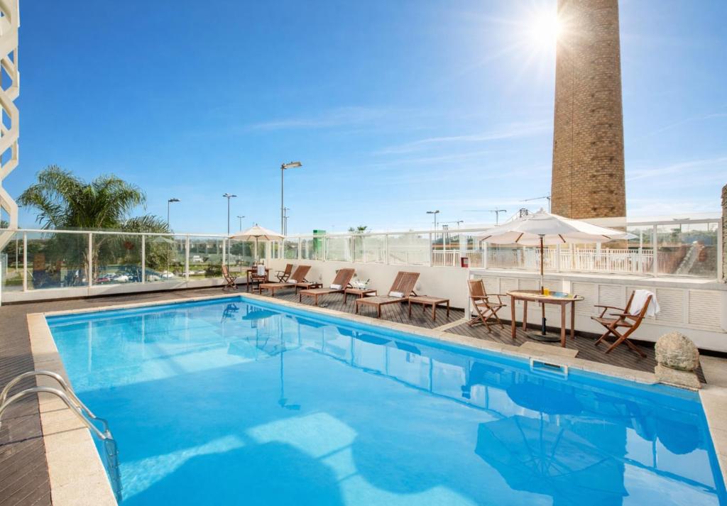 a pool at a hotel with chairs and a table at Intercity Florianopolis in Florianópolis