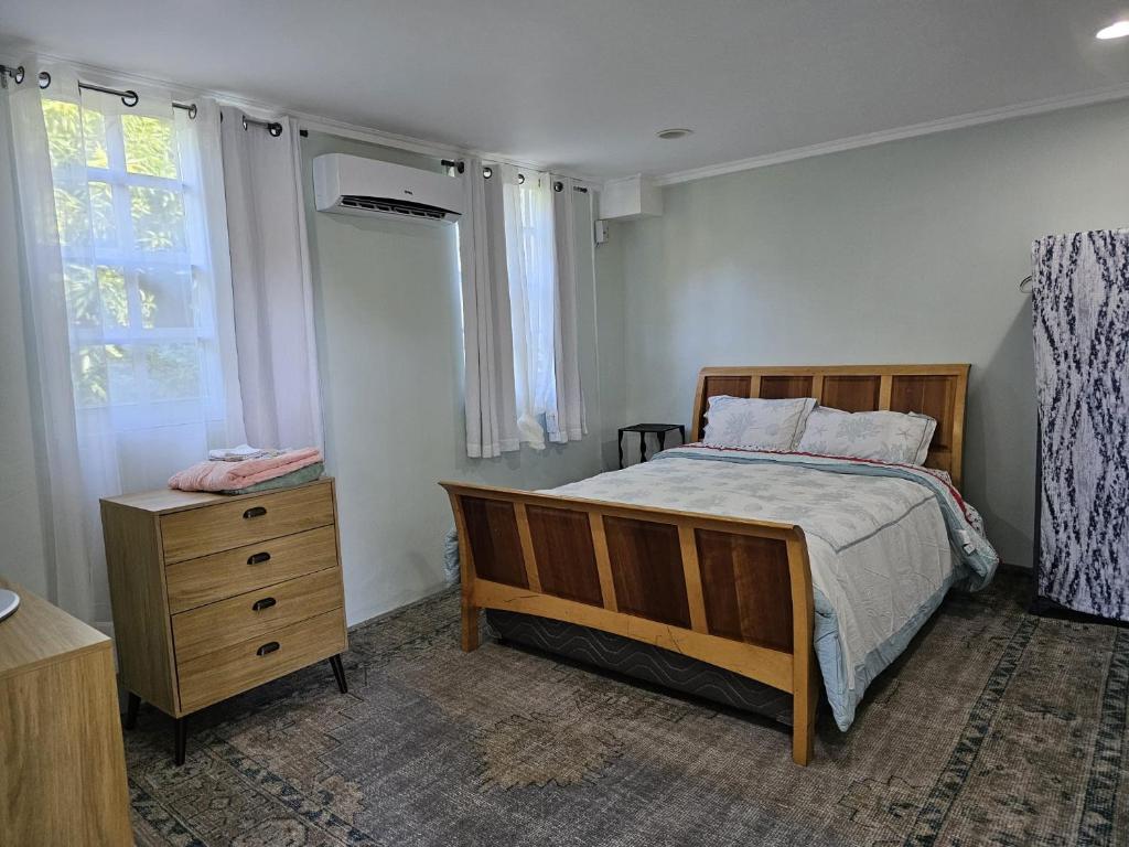 a bedroom with a bed and a dresser and a window at Modern 1 Bedroom Apartment Near Roseau in Canefield