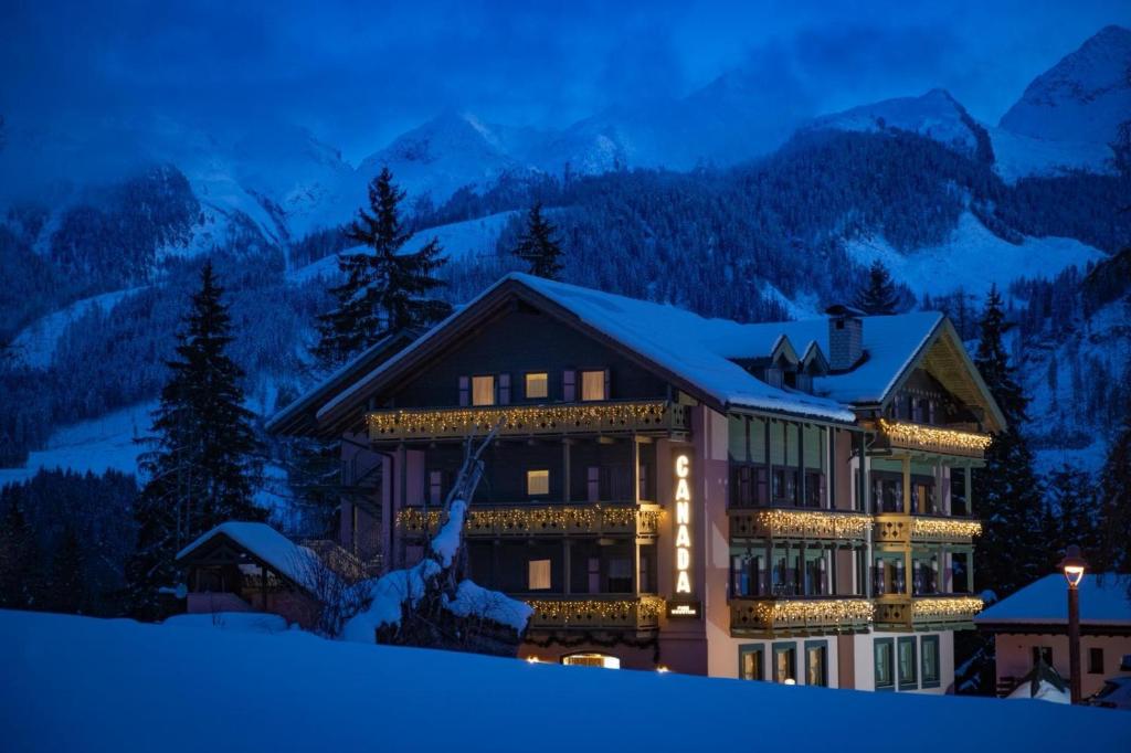 a hotel in the mountains at night in the snow at Hotel Canada in Predazzo
