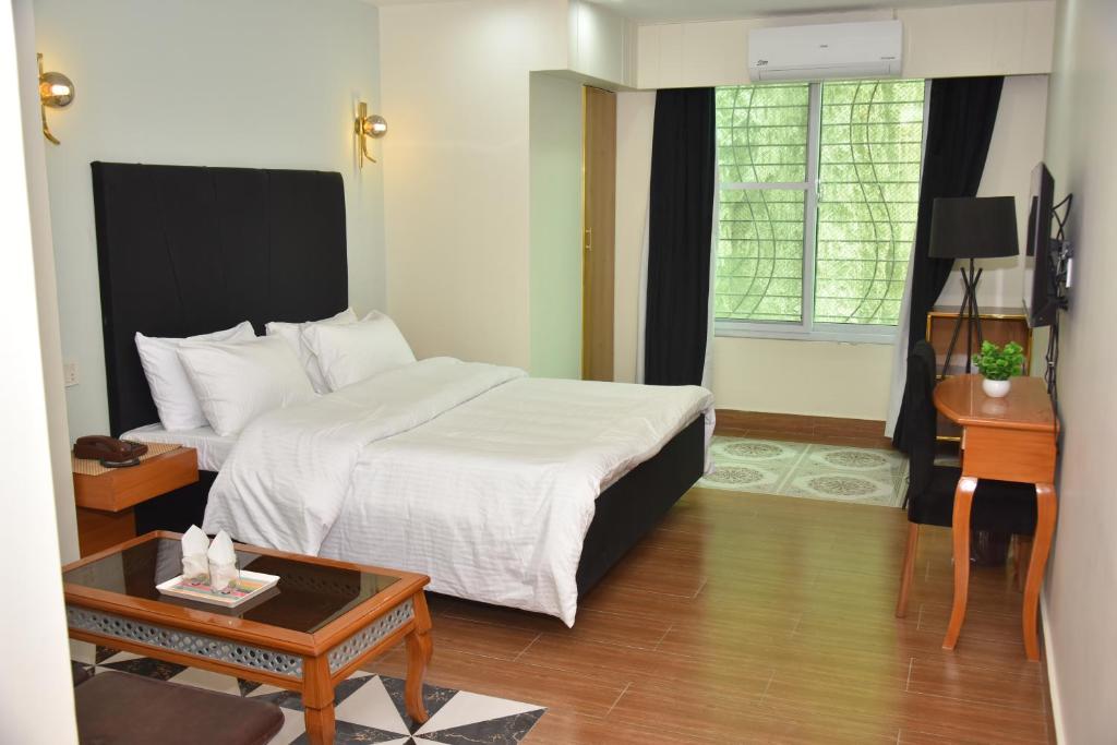 a hotel room with a bed and a table at Modern Hotel with Free Wi-Fi Parking,210 in Muzaffarabad