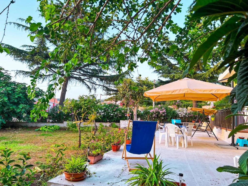 a patio with a blue chair and an umbrella at Casa Primula - Family Country House immersa nel verde a 5 min dal Mare in Ricadi