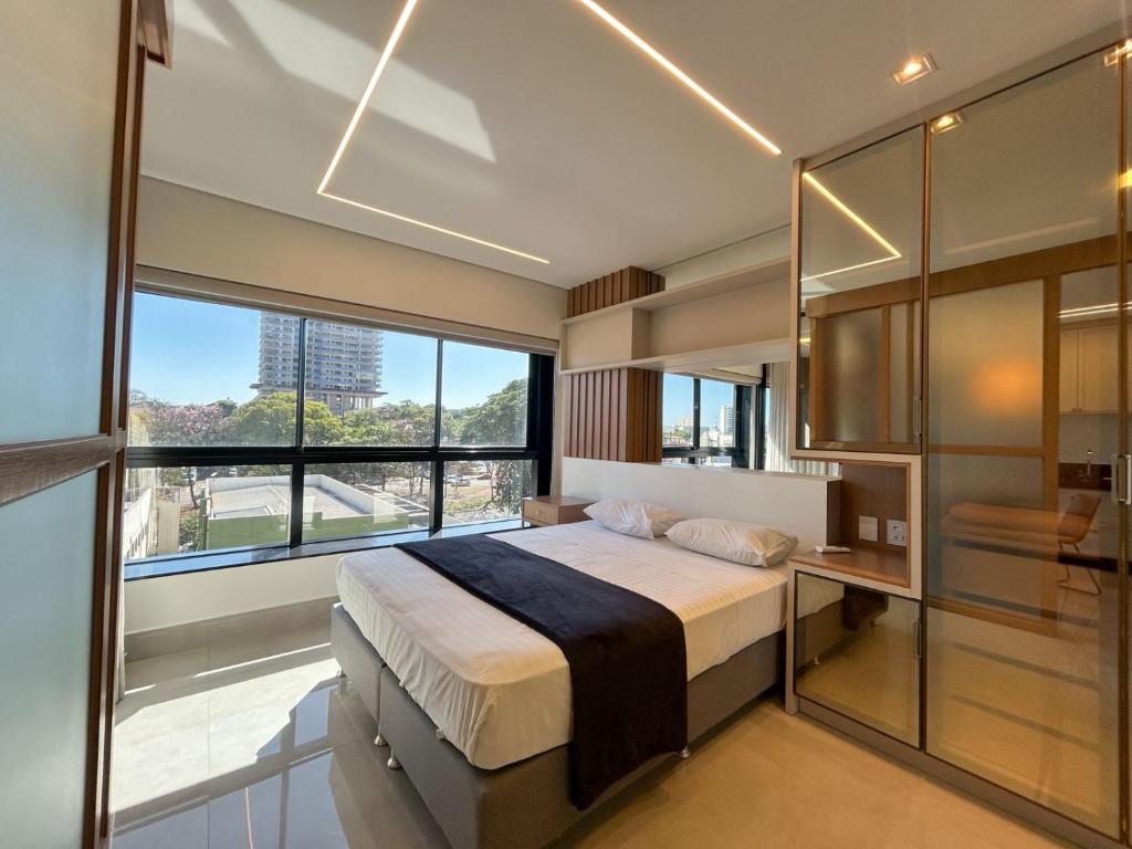 a bedroom with a large bed and a large window at Studio Central, Tranquilo e Confortavel in Campo Grande
