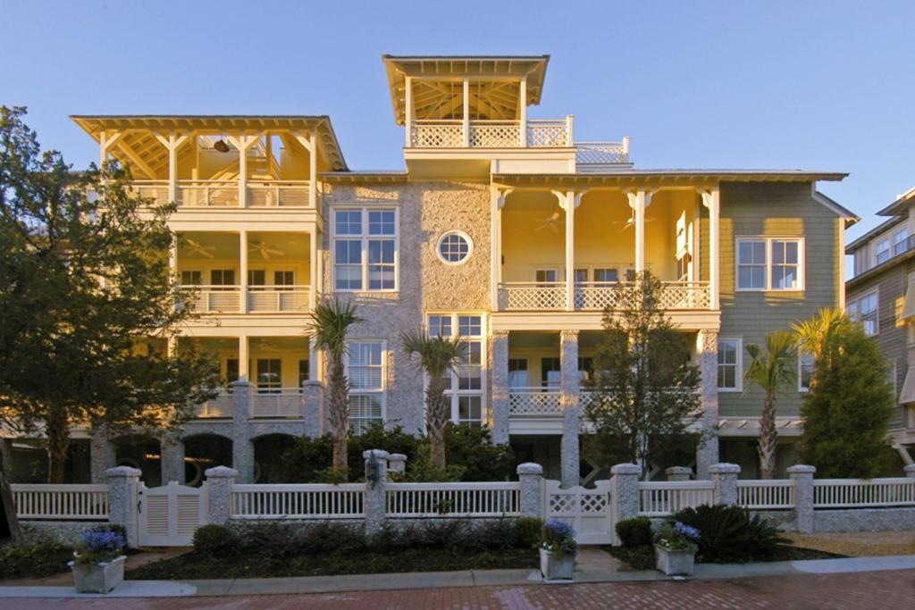 a large yellow house with a white fence at Beach cottage with private pool & spa, ocean views, & shared pool access in Saint Simons Island