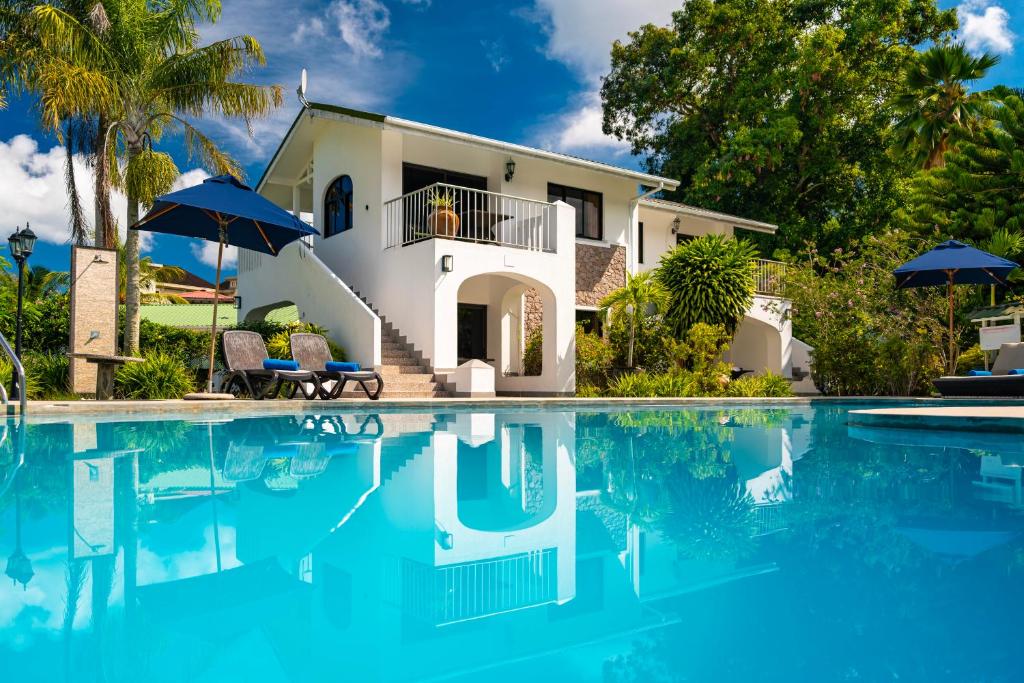 a house with a swimming pool in front of a house at Sun Properties and Resort Hotel in Beau Vallon