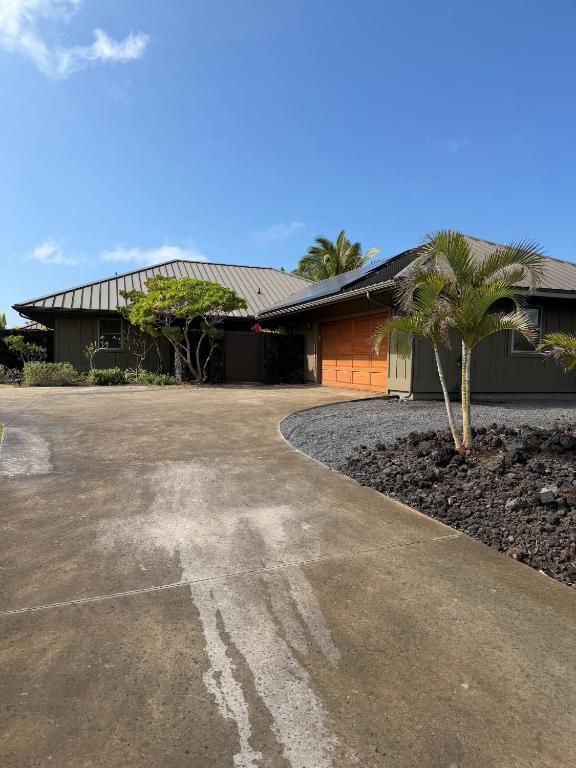 a house with a palm tree in front of a driveway at Ainamalu 9 in Waikoloa