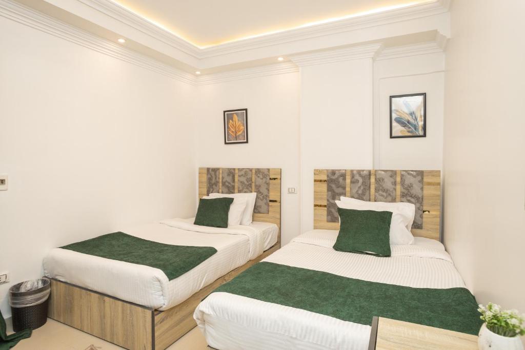 two beds in a white room with green sheets at Museum Land Boutique Hotel in Cairo