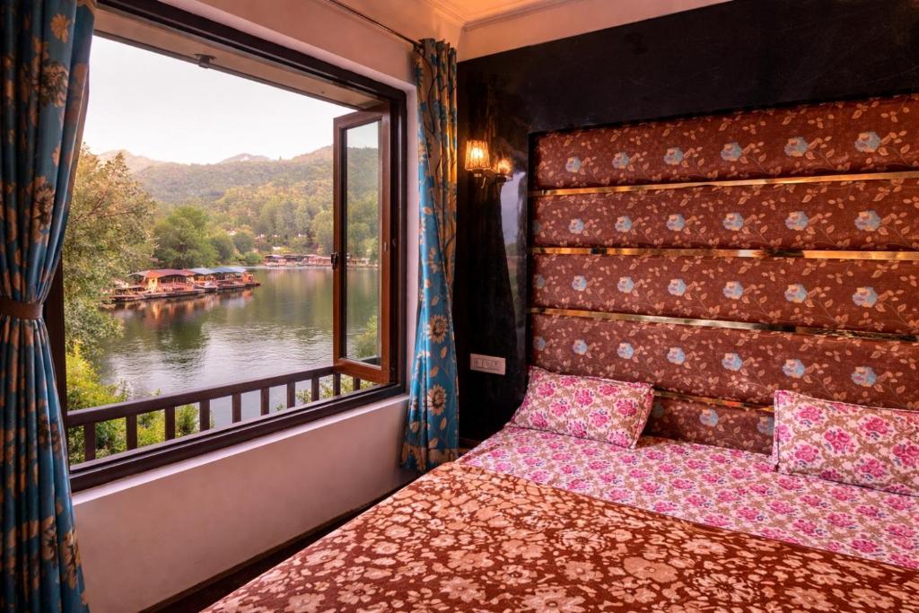 a bed in a room with a window overlooking a river at Lake side stays in Srinagar