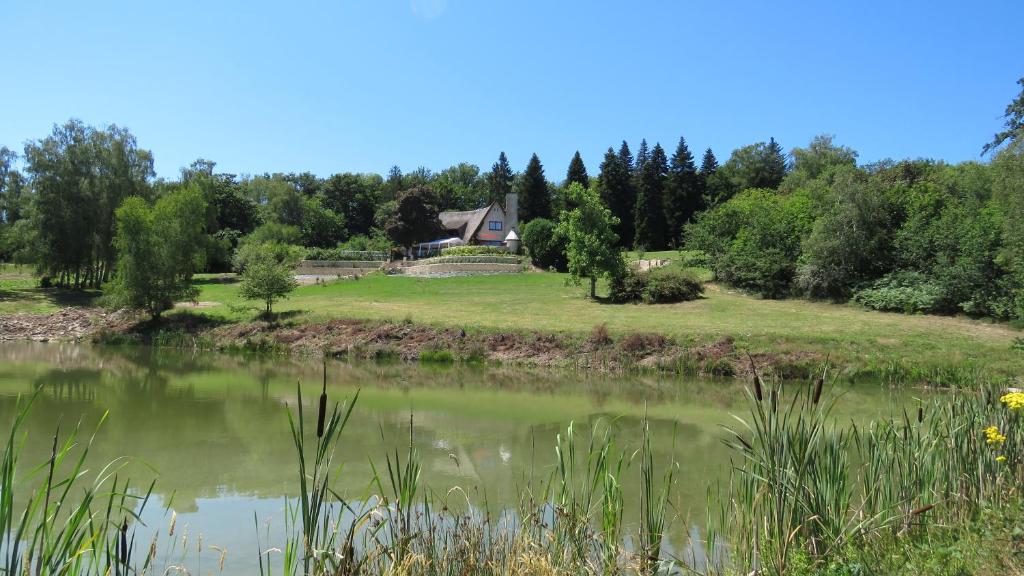 a house on a hill next to a pond at les bois de saint auvent in La Geneytouse