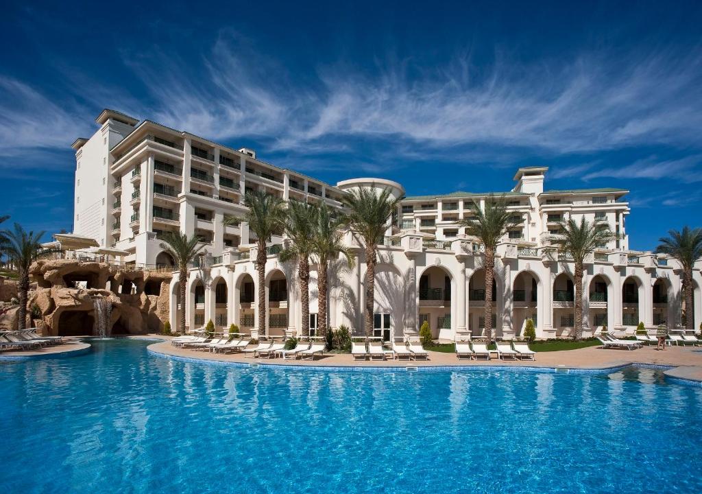 un complexe avec une grande piscine en face d'un bâtiment dans l'établissement Stella Di Mare Beach Hotel & Spa, à Charm el-Cheikh