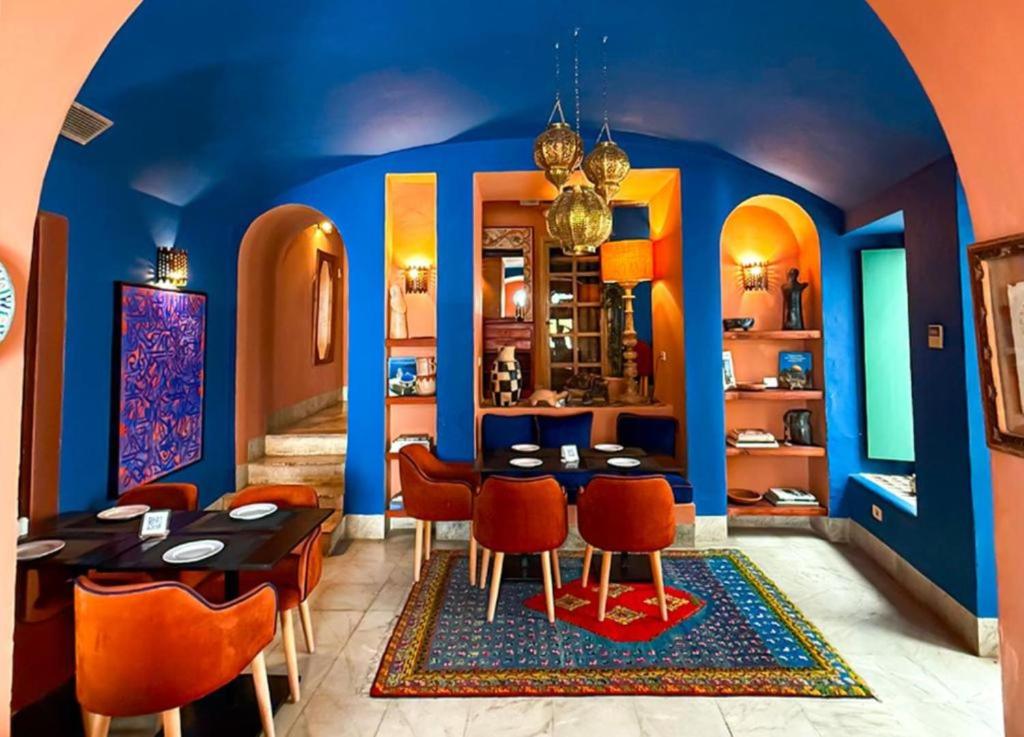 a dining room with blue walls and orange chairs at Dar El Médina in Tunis