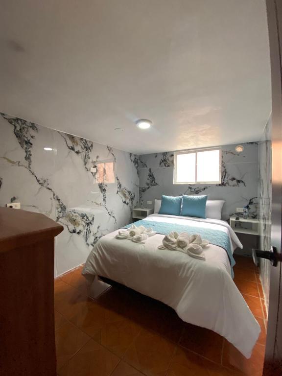 a bedroom with a king sized bed with blue pillows at Dalejadrohouse in Baños