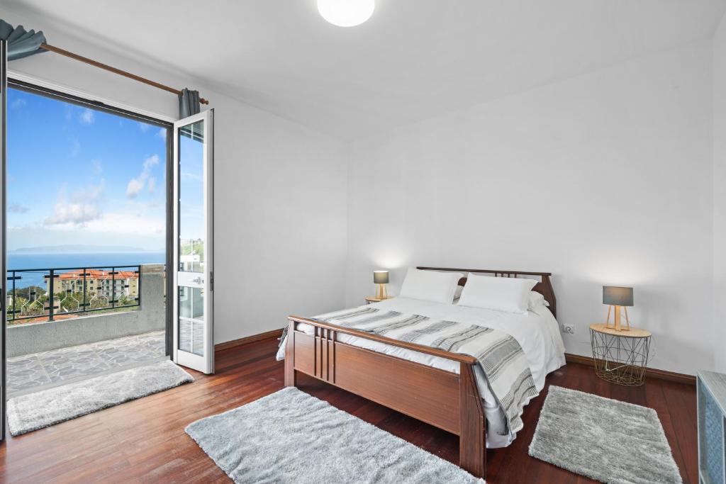 a bedroom with a bed and a large window at Caniço Seaview House in Caniço
