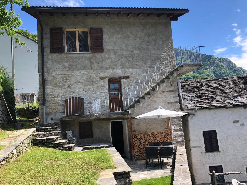 a house with a staircase and a table and an umbrella at Casa Onsernone in Comologno in Comologno